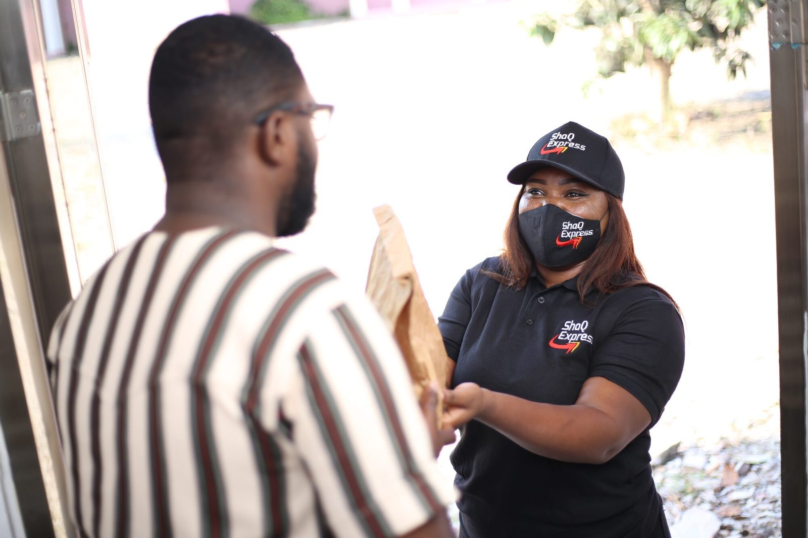 A ShaQ Express team member handing a parcel to a customer at the door