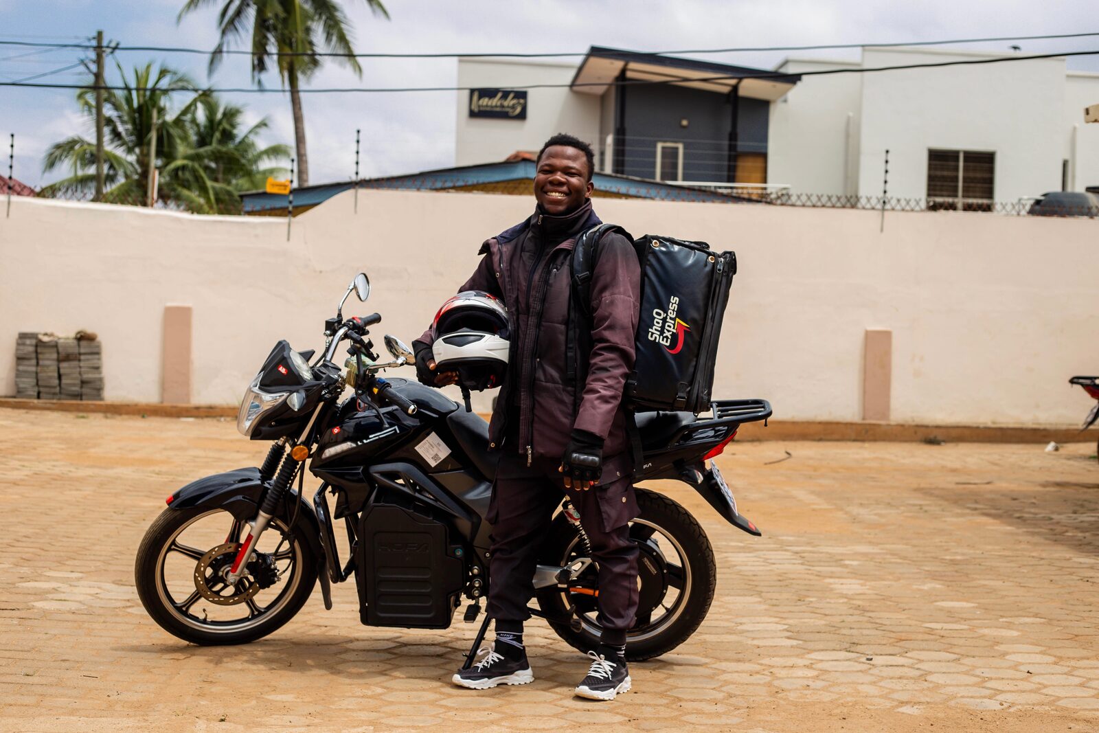 ShaQ Express rider standing beside a KOFA electric delivery motorbike in Accra